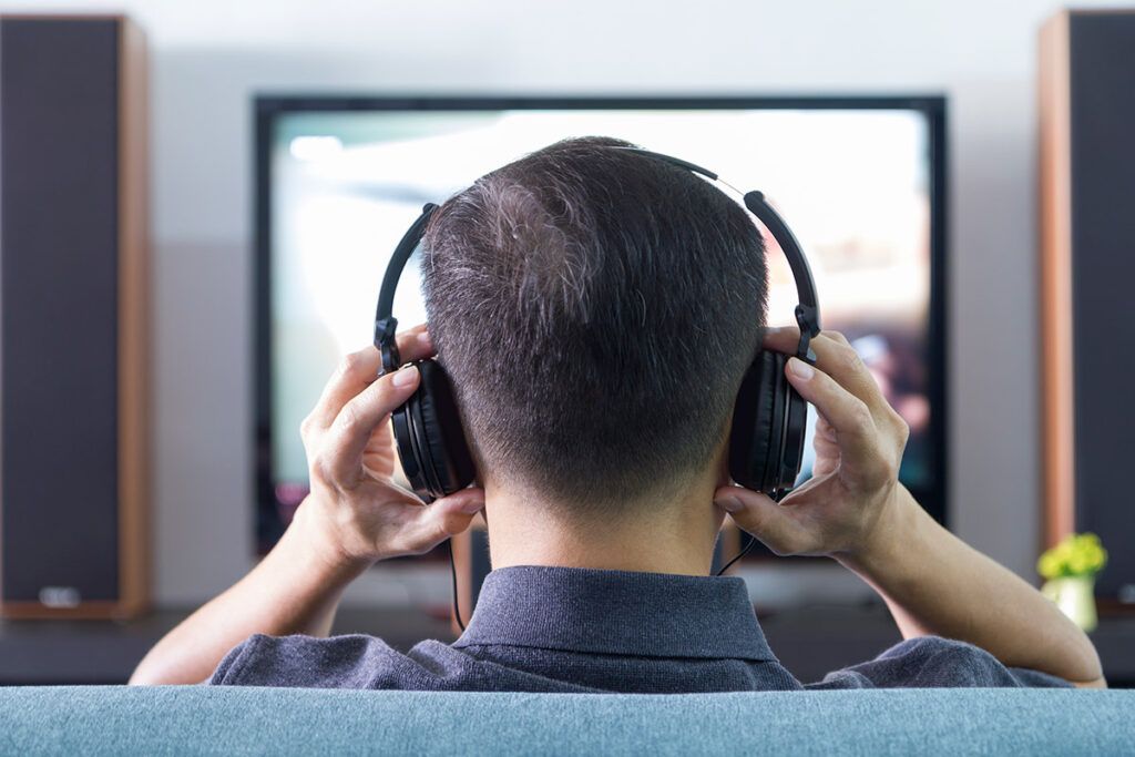 photo of a man watching TV with wireless headphones